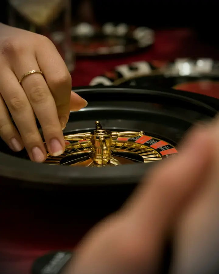 A hand placing a ball on a roulette wheel